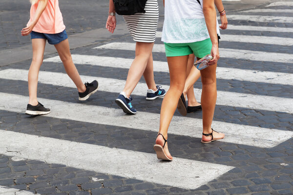 Summery clothed people crossing the street at the pedestrian crossing