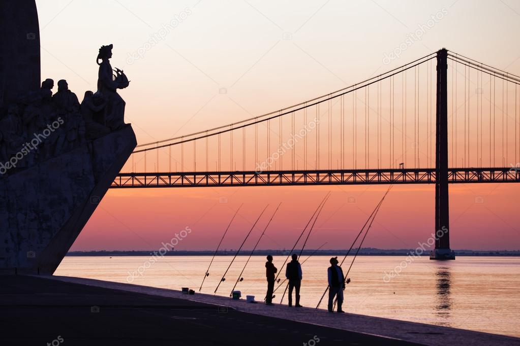 Silhouettes of anglers at the Tagus River in Lisbon, Portugal, before sunset