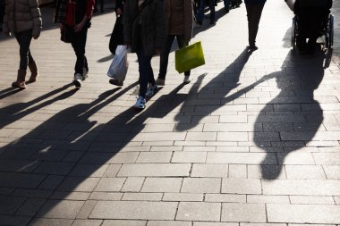 Uzun gölgeler ile şehirde yürüyüş insanlar alışveriş