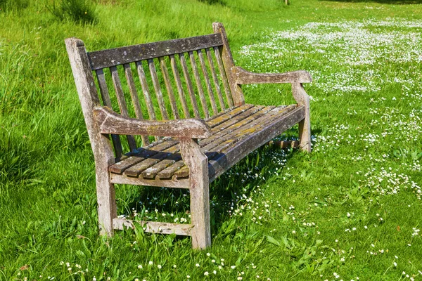 ที่นั่งสวนสาธารณะแห้งแล้งเก่าบนทุ่งหญ้าสีเขียว — ภาพถ่ายสต็อก