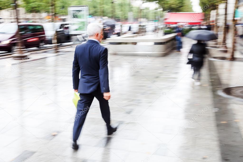 Businessman walking in the rainy city in motion blur