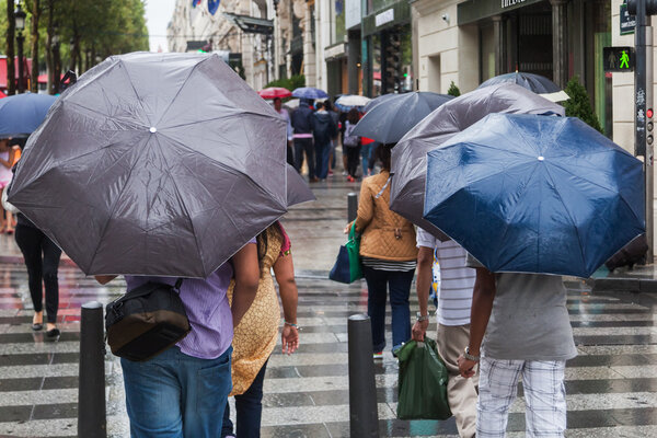 People with rain umbrellas crossing a city street on a rainy day