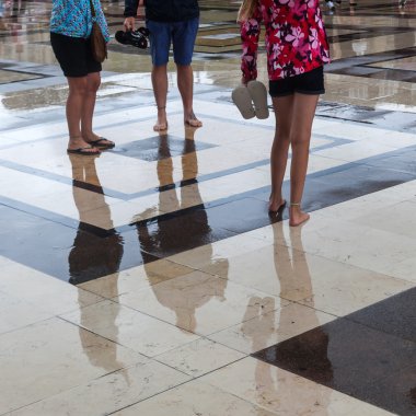 Bir yağmurlu ıslak şehir meydanında yalınayak insanlar