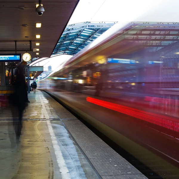 El tráfico ferroviario en movimiento se desdibuja en una plataforma de una estación ferroviaria — Foto de Stock