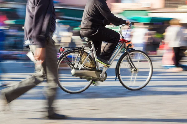 Ciclista em movimento borrão em uma praça da cidade — Fotografia de Stock