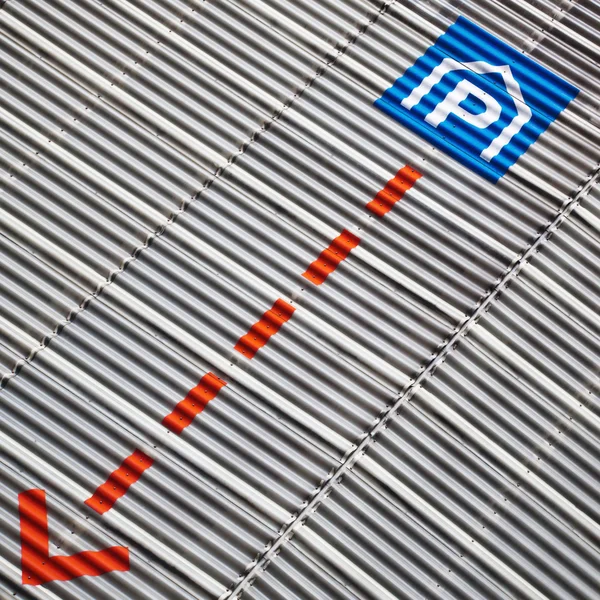 Segno di parcheggio e una freccia su una facciata in lamiera ondulata — Foto Stock
