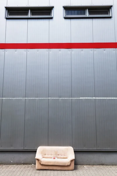 Endüstriyel bir binanın önünde bir kaldırımda kanepe — Stok fotoğraf