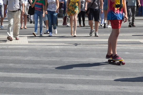 Skara människor och en skateboardåkare passerar en gata — Stockfoto