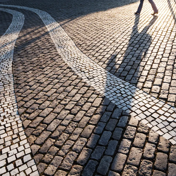Shadow of a walking person on a cobblestone square — Stock Photo, Image