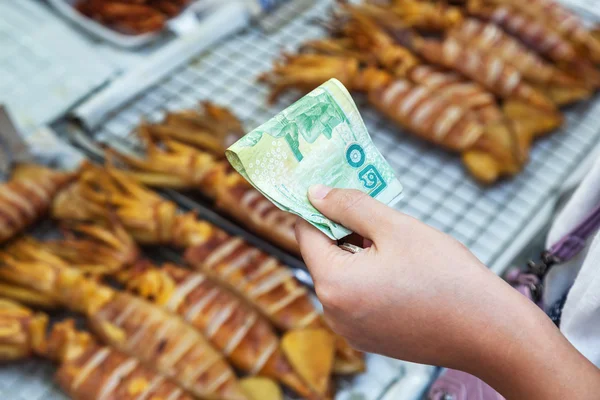 Mão com Baht tailandês pagando em uma loja de culinária em Bangkok, Tailândia — Fotografia de Stock