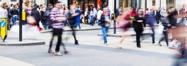 Crowd of people in motion blur crossing a city street clipart
