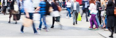 Crowd of people in motion blur crossing a city street clipart