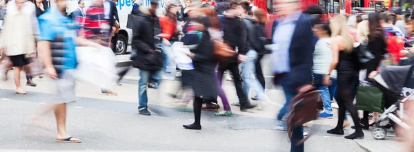 Menigte van mensen in bewegingsonscherpte oversteken van de straat van een stad — Stockfoto