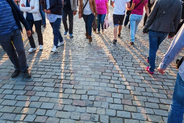 People crowd in backlit walking on cobblestone road — Stock Photo, Image