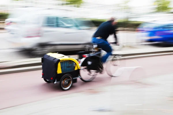 Cavalier à vélo avec une remorque à vélo dans la circulation urbaine en mouvement flou — Photo