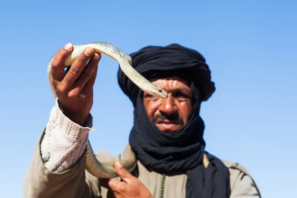 Tuareg hombre con turbante sosteniendo serpiente en la mano — Foto de Stock