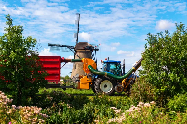 Tracteur avec tondeuse en action dans les célèbres moulins à vent de Kinderdijk, Pays-Bas — Photo