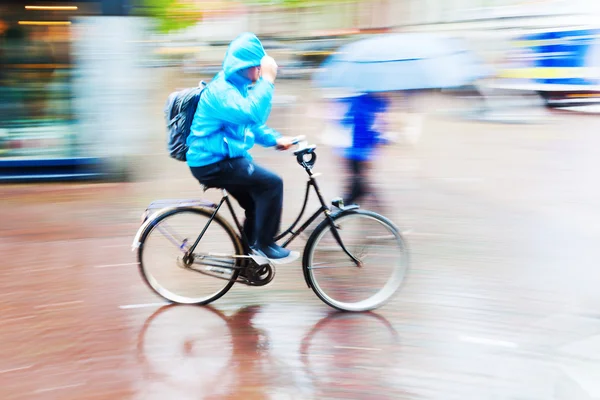 雨の多い街で自転車に乗る人 — ストック写真