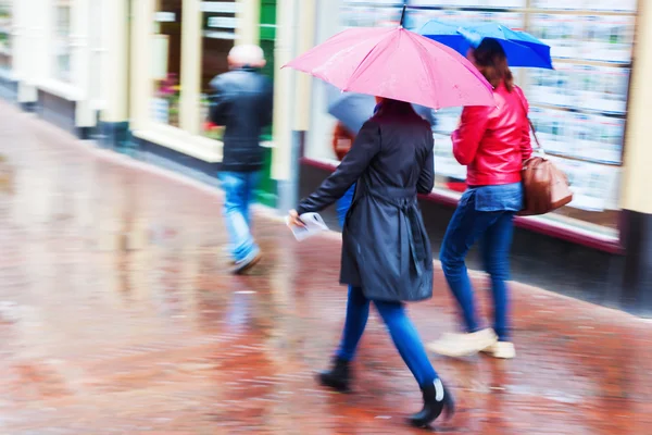 Женщины с зонтиками прогуливаются по дождливому городу — стоковое фото