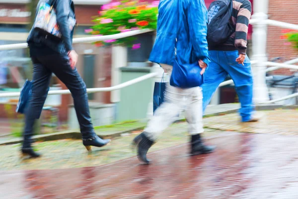 Människor som vandrar i regniga staden i rörelse oskärpa — Stockfoto