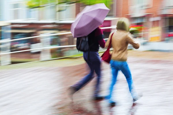 Lidí, kteří jdou v deštivé městě v pohybu rozostření — Stock fotografie