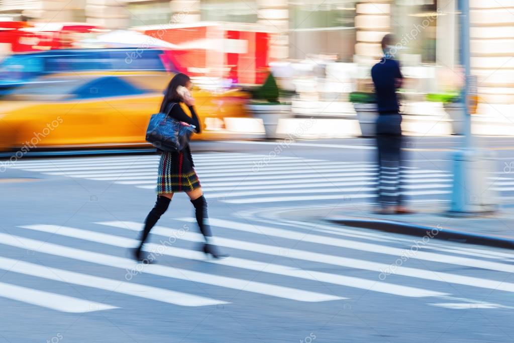 woman crossing a street while she is phoning