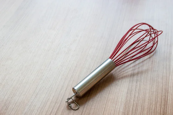 Red stainless whisk on wood — Stock Photo, Image