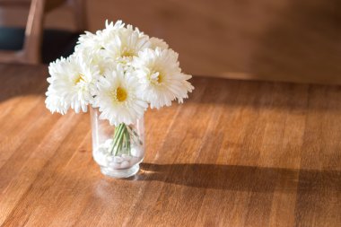 wase ahşap masa üzerinde beyaz yapay papatya çiçeği