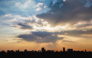 # Bulutların arkasında güneş ışığı ve gölgeli şehir manzarası # Alacakaranlık vakti