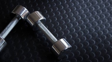 Spor salonunda kauçuk zeminde demir dambıl.