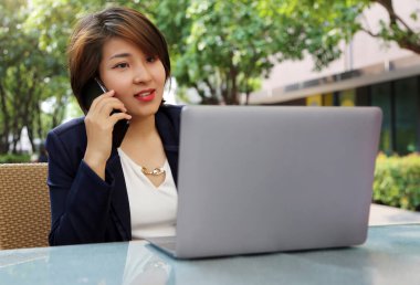 Serbest çalışan Asyalı kadın iş kurdu ve evde çalıştı, iş kadını dizüstü bilgisayarda çalıştı ve cep telefonu kullandı..