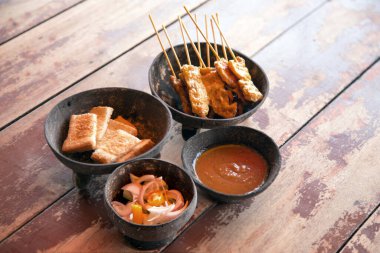 Hint cevizi tabağında odun çubuğuyla körili domuz ızgara servis et. Tahta masa üzerinde servis yap. Tayland sokak yemekleri konseptinde.