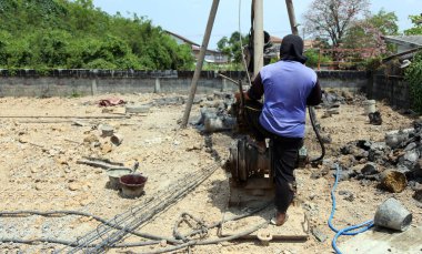 İşçi, bina inşaatındaki kazığı en alt açıdan kontrol ediyor.