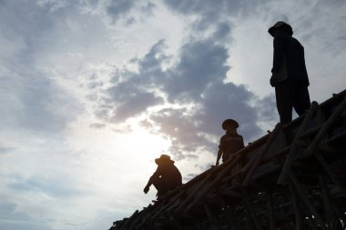 Gün batımında inşaat alanında insan gücü silueti.