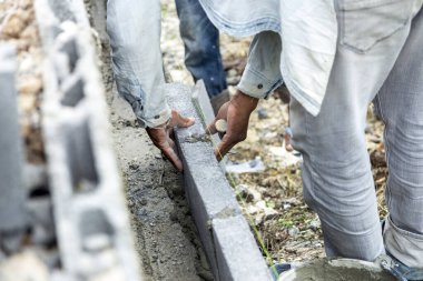 Güvenli ev için tuğlalı çit yapmak için işçilerin elini kapatın.