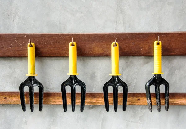 Gardening tools, black iron rake with plastic handle hanging on — Stock Photo, Image