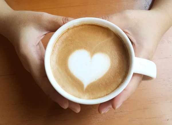 Hand hålla kopp latte art kaffe — Stockfoto