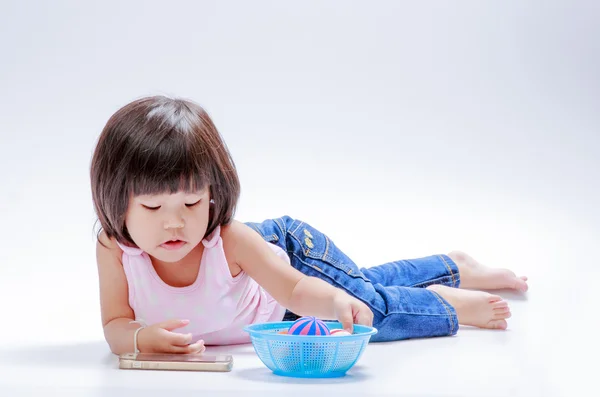 Menina asiática assistindo celular e jogar bola — Fotografia de Stock