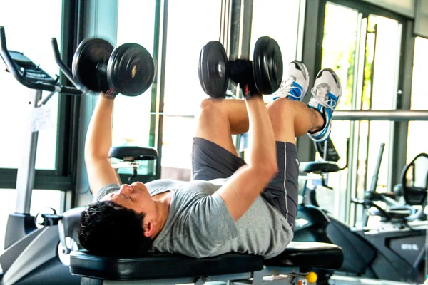 man work out with dump bells in fitness