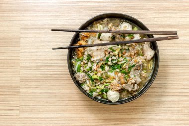 ahşap sopa ile siyah kasede beyaz makarna ve çorbası domuz eti