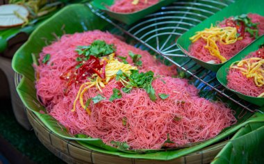 Geleneksel Tayland Pembe Eriştesi veya Mee Kati muz yapraklarıyla servis edilir. Paramparça yumurta ve kırmızı biberle kaplı canlı pembe pirinç vermicelli. Popüler otantik Tayland sokak yemekleri.