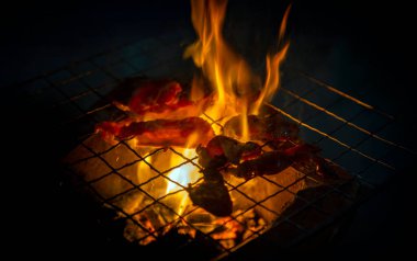 Sıcak kömürün üzerinde ateşte kızartılan etin yakın çekimi. BBQ için otantik Asya sokak yemekleri, açık hava yemekleri ve gece hayatı yemek deneyimleri.