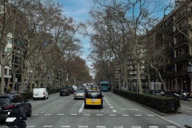 11 Şubat 2026, Bacelona, İspanya: Avinguda Diagonal caddesinde kış ağaçları ve kentsel mimarinin yer aldığı ikonik siyah ve sarı taksilerle trafik