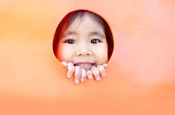 アジアの女の子はプラスチックの穴から外を見て — ストック写真