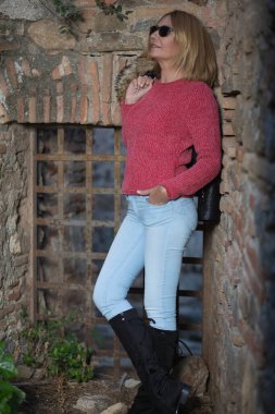 Elleri ceplerinde, kameradan uzağa bakan sıradan bir kadın.