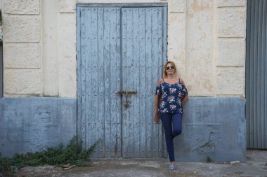 Yaşlı, yıpranmış ahşap kapının yanında dikilen kadın.