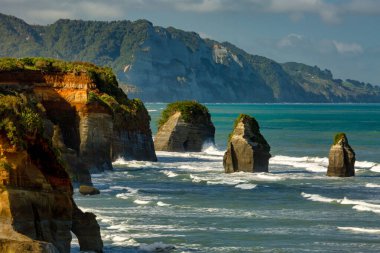 Taranaki Dağı 'nın karla kaplı volkanik konisi Taranaki' deki Tongaporutu plajında dramatik üç kız kardeşin önünde.