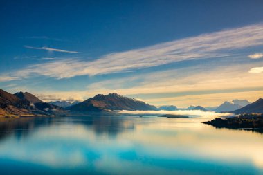 Güney Alpleri 'nin çarpıcı panoramik manzarası ve Wakatipu Gölü' nün sakin sularına yansıyan dağ yansımaları. 
