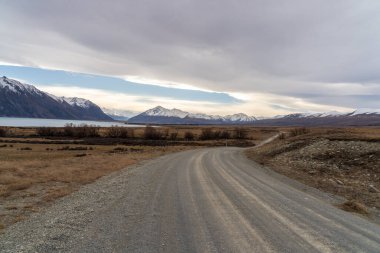 Tekapo Gölü 'nün kıyısındaki Lilybank yolundan karlı Cook Dağı sıradağlarına doğru gidiyor.