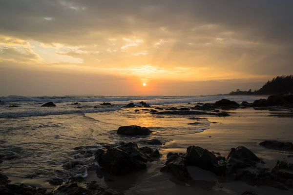 Pôr do sol de verão na praia rochosa em frente ao hotel à beira-mar de 6 estrelas para umas férias escondidas perfeitas sozinhas ou ainda melhores com a família que pode desfrutar de atividades ao ar livre, frutos do mar e estadia inesquecível Fotos De Bancos De Imagens